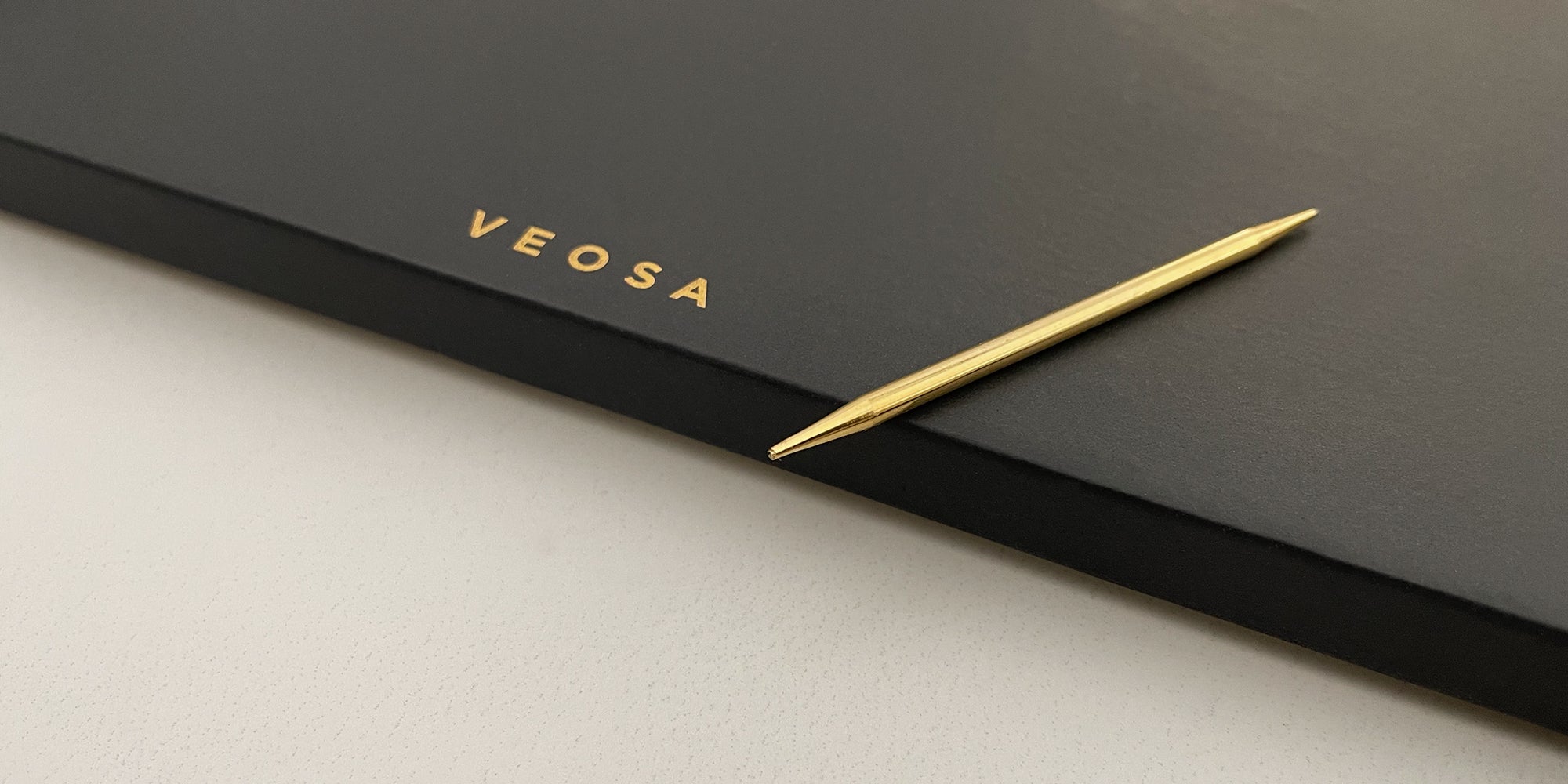 gold toothpick sitting on charcoal ceramic tray with gold veosa logo